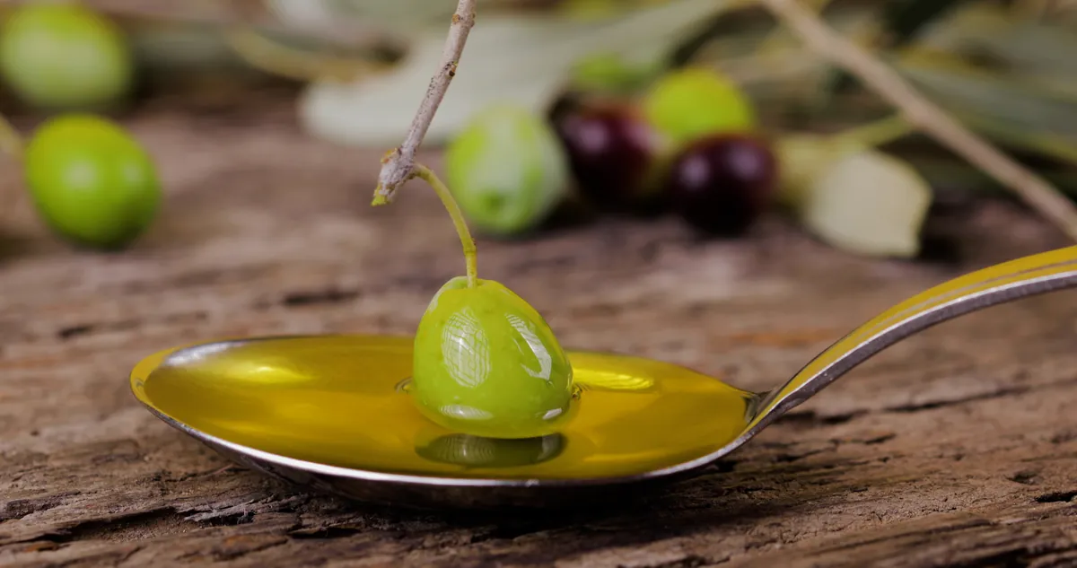Aceite con una aceituna sobre una superficie de madera rústica