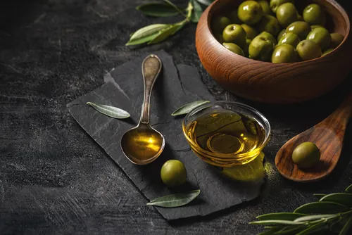 Aceite de oliva y aceitunas verdes sobre un fondo negro