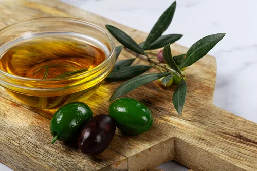 Aceite servido junto a unas aceitunas y una rama