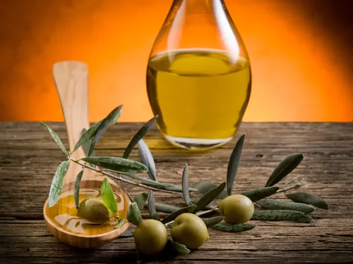 Aceite y aceitunas colocados sobre una superficie de madera clara