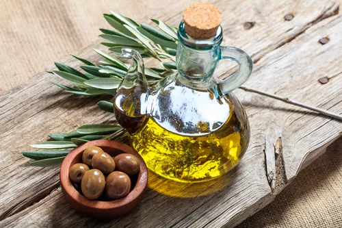 Aceite y aceitunas dispuestos sobre una tabla rústica desgastada