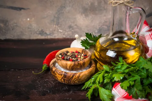 Aceite acompañado de pimientas y especias sobre la mesa