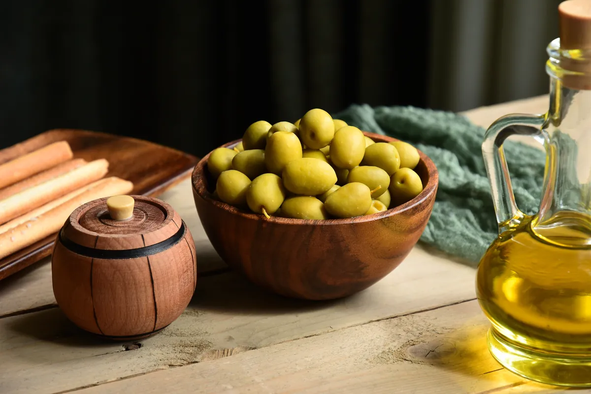 Aceitunas verdes y aceite dispuestos sobre la encimera de cocina