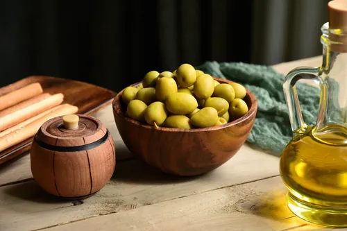 Aceitunas verdes y aceite dispuestos sobre la encimera de cocina
