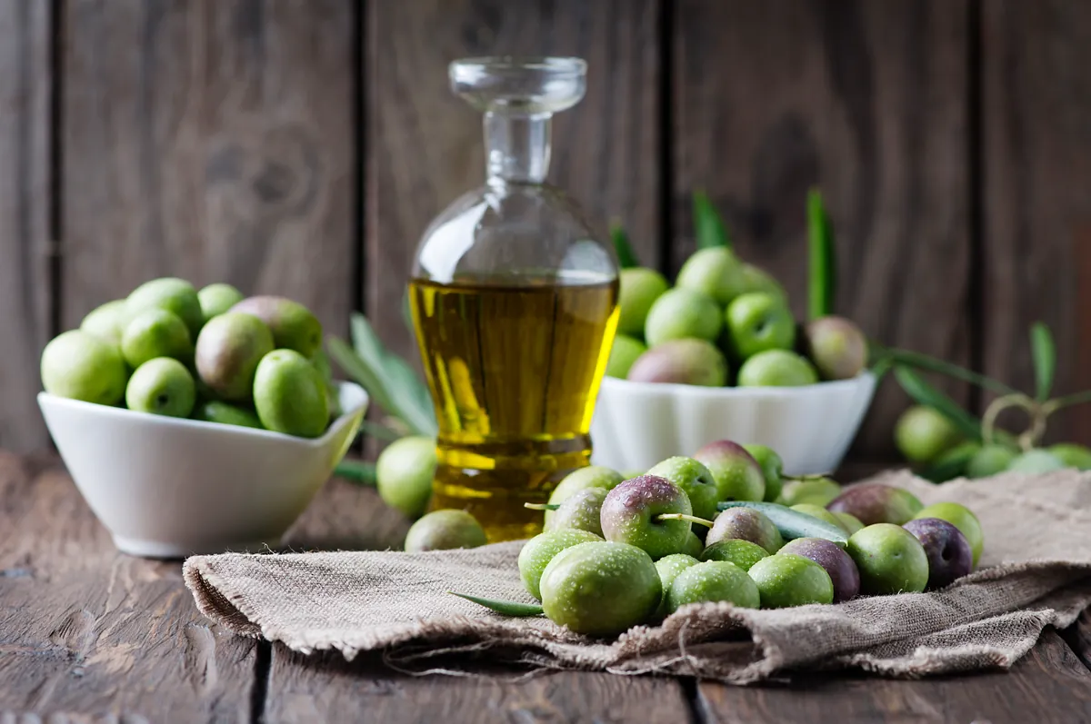 Aceitunas y aceite colocados sobre una mesa rústica de madera