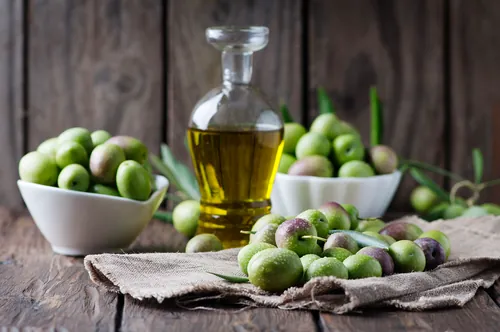 Aceitunas y aceite colocados sobre una mesa rústica de madera
