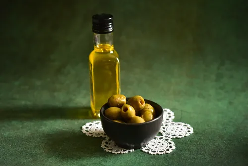 Aceitunas verdes y aceite dispuestos sobre una mesa verde