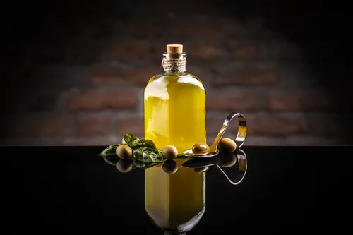 Aceitunas verdes colocadas junto a un recipiente con aceite