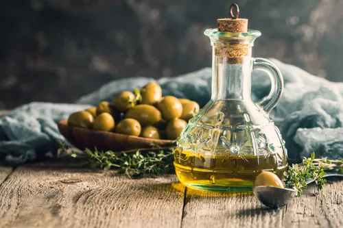 Bodegón de aceite y aceitunas dispuesto sobre una mesa