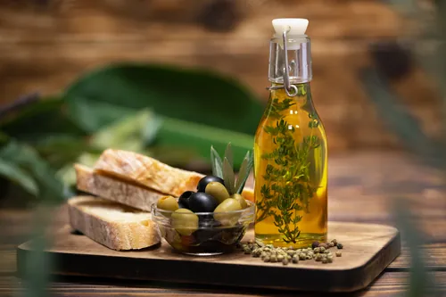 Botella de aceite de oliva junto a aceitunas y pan rústico