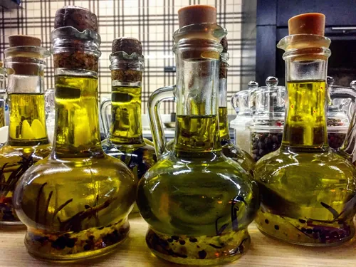 Botellas de aceite de oliva acompañadas de hierbas y especias