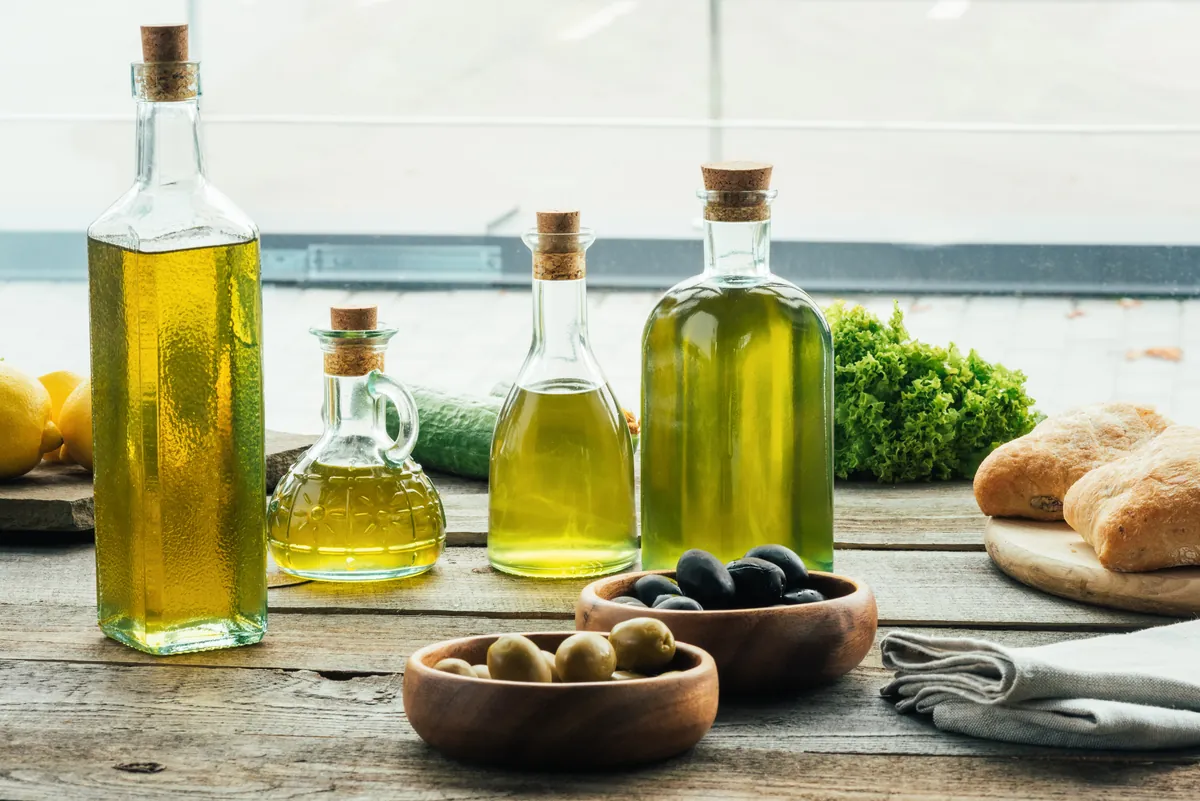 Botellas de aceite con aceitunas y pan de corteza crujiente