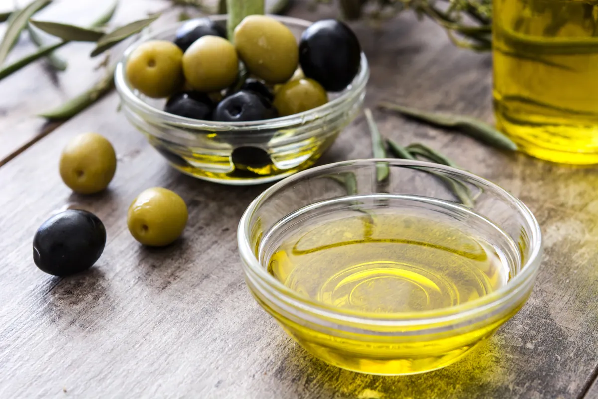 Cuenco de aceitunas junto al aceite sobre la mesa