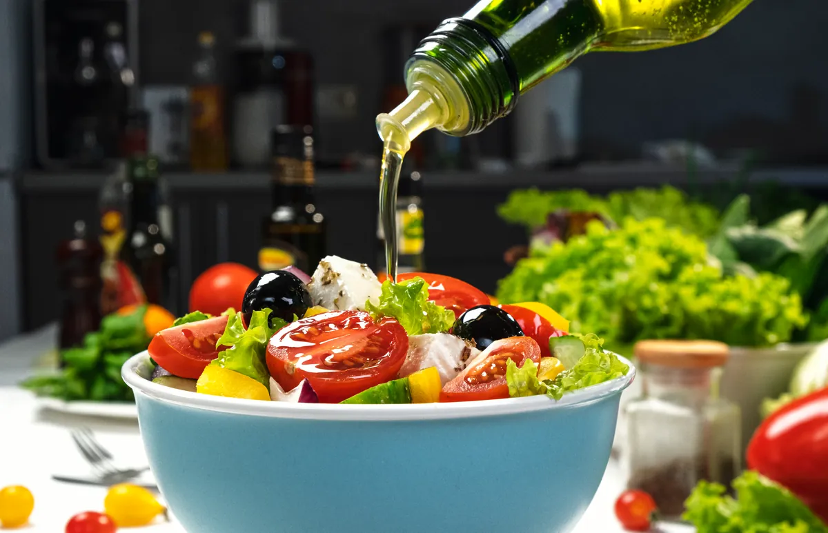 Ensalada fresca siendo aliñada con un chorro de aceite