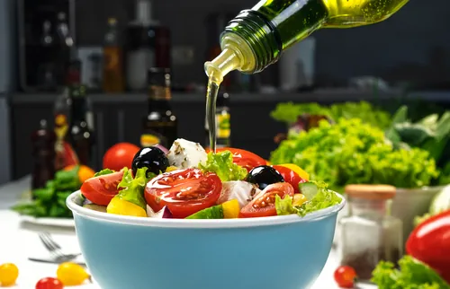 Ensalada fresca siendo aliñada con un chorro de aceite