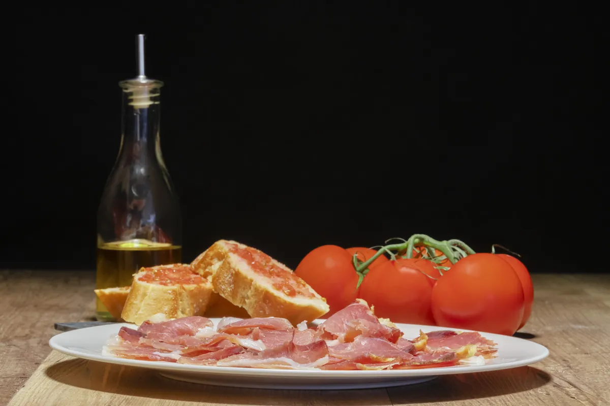Plato de jamón con pan y tomate recién preparado