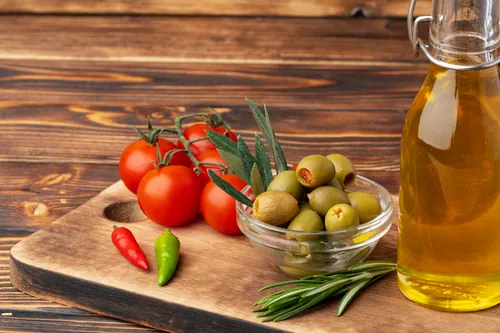 Tomates aceitunas pimientos y aceite sobre una tabla de madera