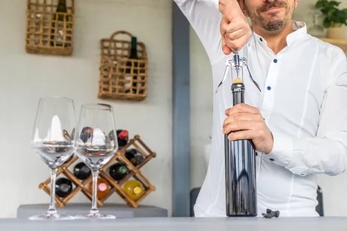 Hombre descorchando una botella de vino en una barra doméstica