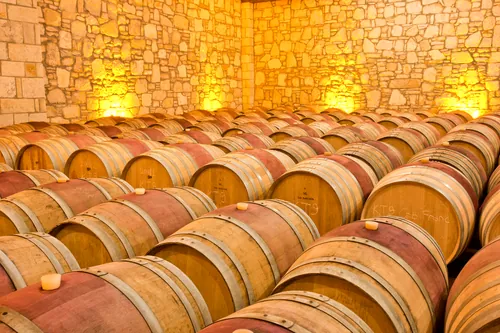 Barricas de madera dispuestas en una bodega de muros de piedra