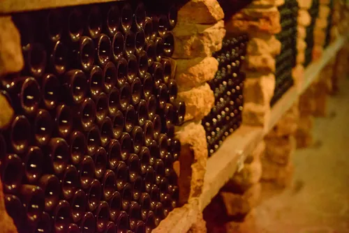 Hileras de botellas de vino envejeciendo lentamente en la bodega
