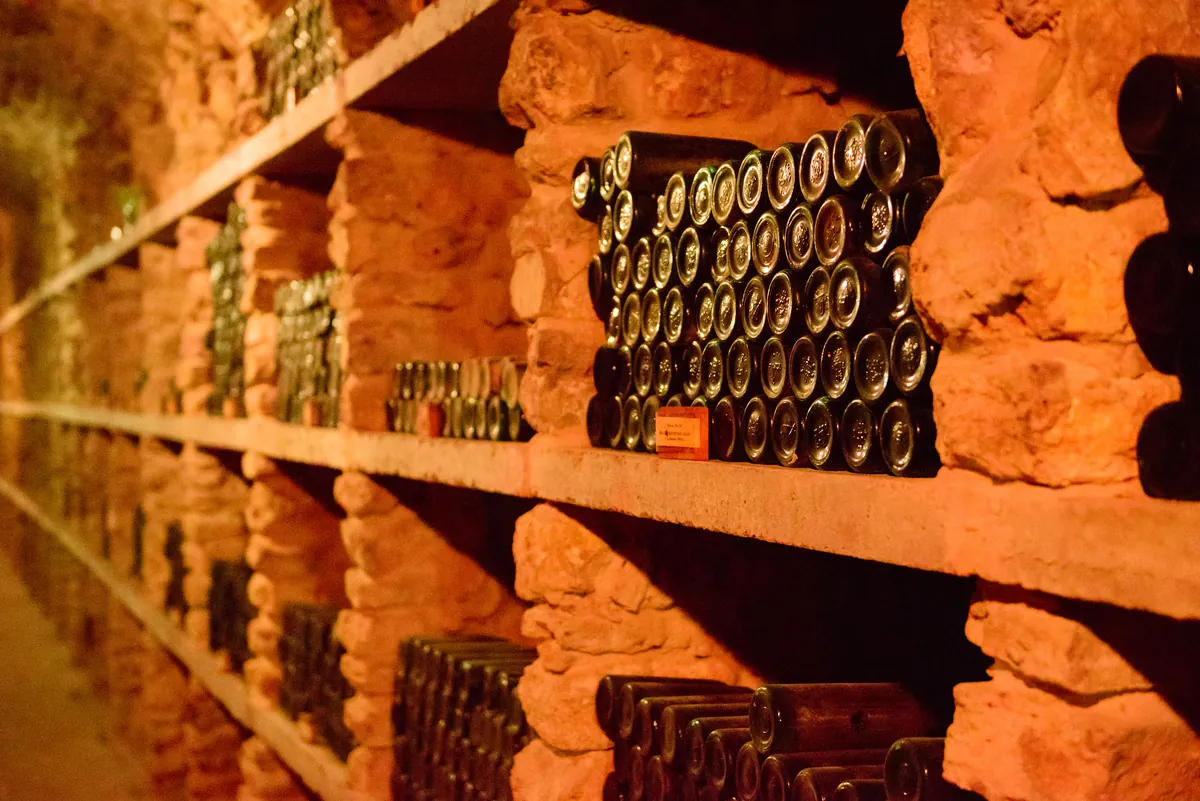 Botellas de vino colocadas en estantes de piedra de la bodega