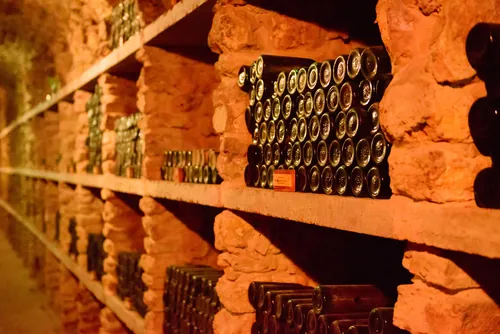 Botellas de vino colocadas en estantes de piedra de la bodega