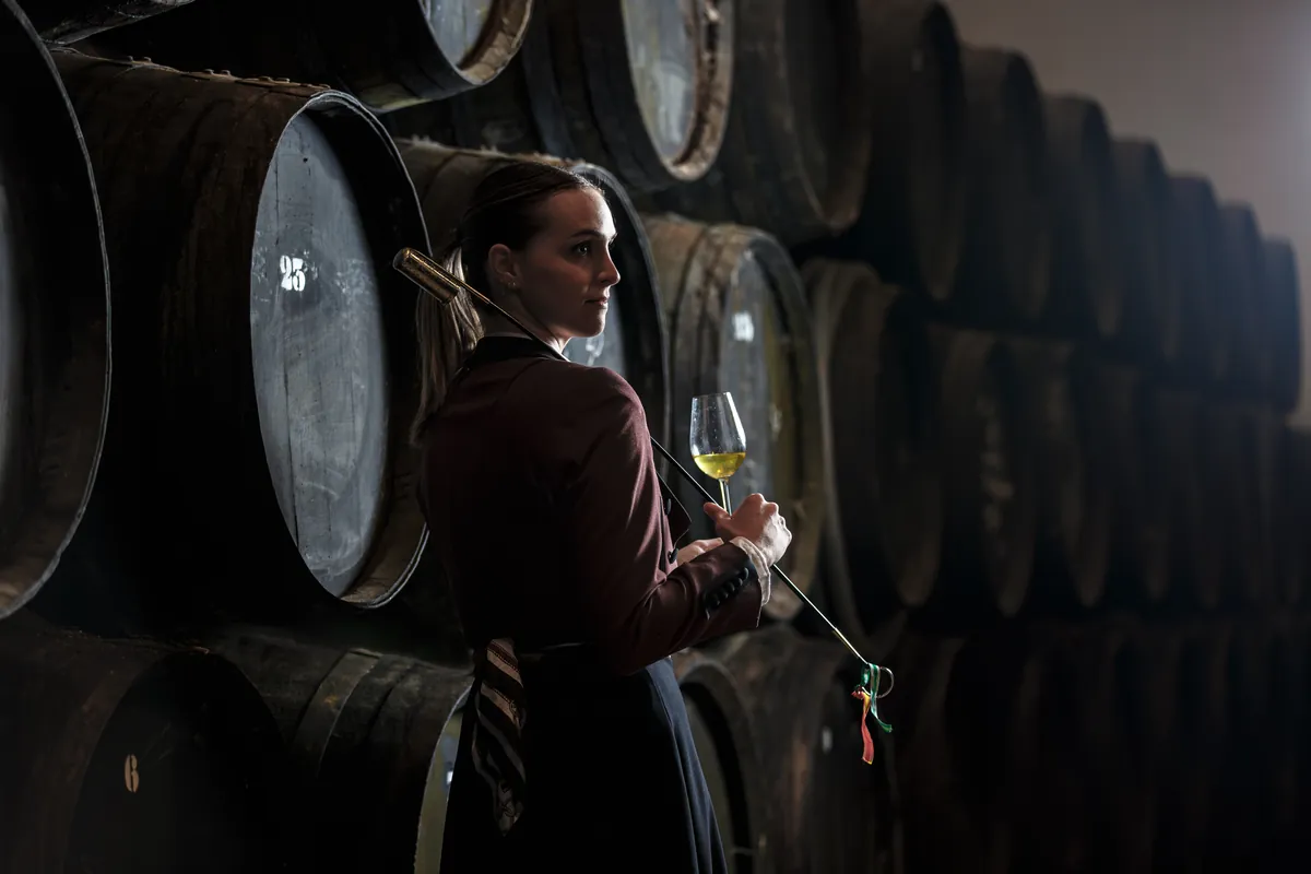 Mujer sosteniendo una copa de vino dentro de la bodega