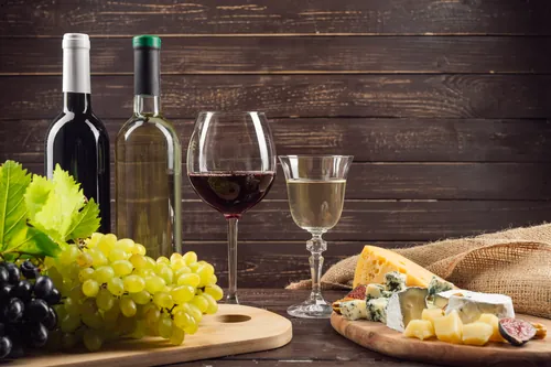 Botellas de vino con uvas y una tabla de quesos