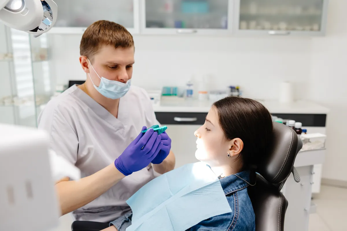 Dentista explicando un molde a una paciente en el sillón de una clínica dental