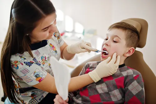 Odontólogo examinando los dientes de un niño en consulta