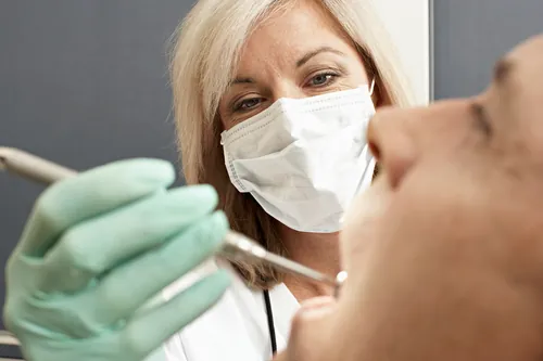 Odontólogo trabajando sobre la dentadura de un paciente tumbado