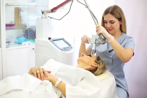 Profesional aplicando un tratamiento láser sobre el rostro de la clienta