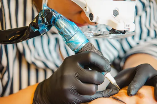 Profesional aplicando maquillaje permanente en las cejas de una clienta