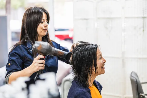 Peluquera dando forma al cabello de una clienta sentada