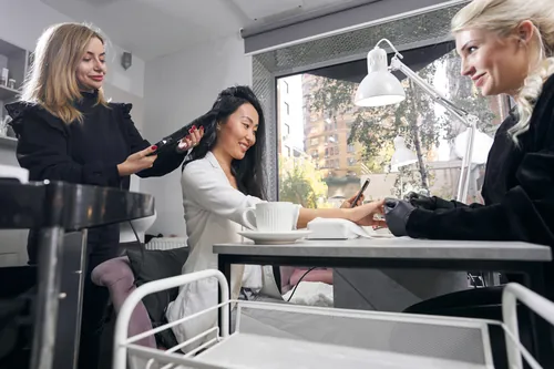 Clientas recibiendo servicios de peluquería y manicura en el salón