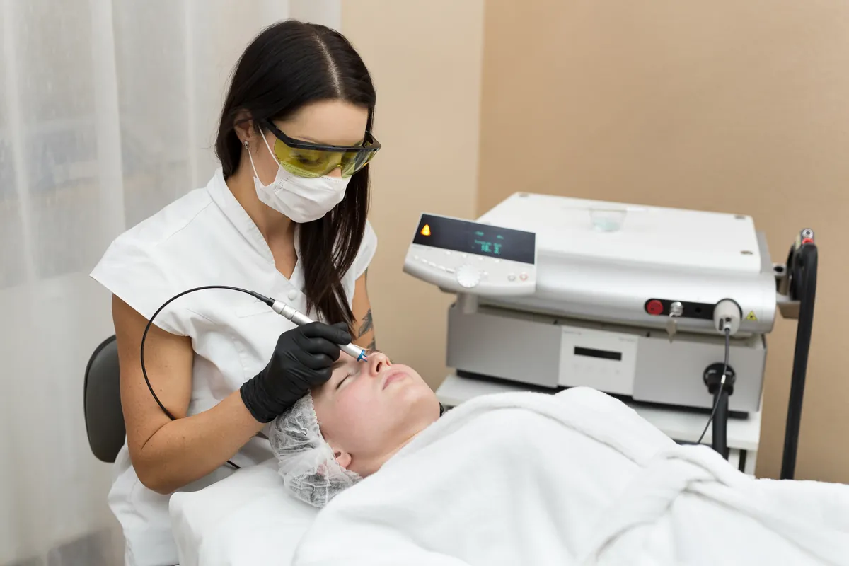 Profesional realizando un tratamiento facial a una clienta tumbada