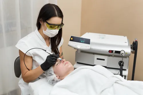 Profesional realizando un tratamiento facial a una clienta tumbada