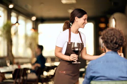 Camarera sirviendo vino a unos clientes en la mesa