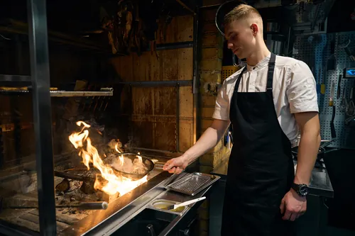 Cocinero sofriendo cebolla y zanahoria en una sartén grande