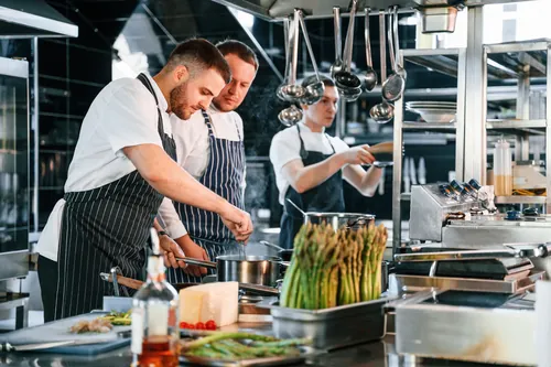 Cocineros elaborando un plato de espárragos en la cocina
