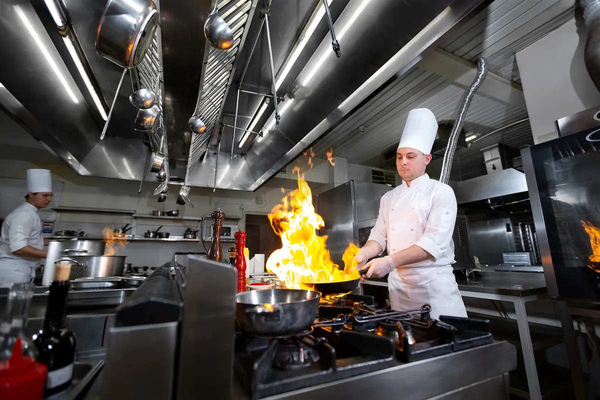 Chef flambeando un plato en plena cocina profesional