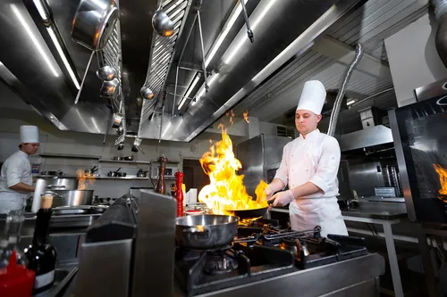 Chef flambeando un plato en plena cocina profesional
