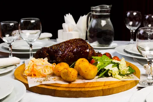 Presentación cuidada de cerdo asado acompañado de verduras