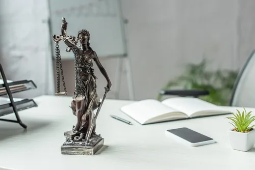Estatua de la justicia sobre una mesa de oficina blanca
