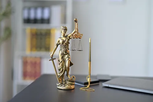 Balanza de la justicia junto a un portátil y un bolígrafo