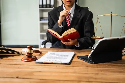 Profesional consultando un manual jurídico en su mesa de trabajo