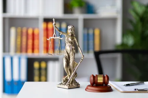 Estatua de la justicia junto al mazo sobre la mesa