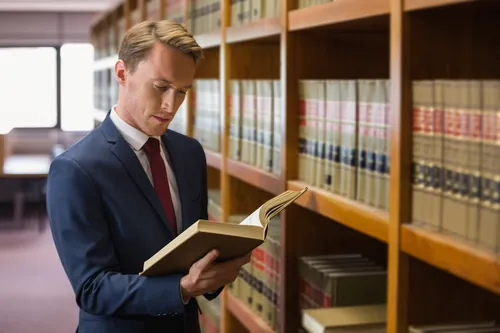 Profesional leyendo un libro en una biblioteca de consulta